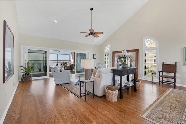 living area featuring high vaulted ceiling, a wealth of natural light, ceiling fan, and wood finished floors