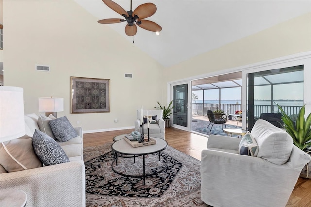 living area with visible vents, high vaulted ceiling, wood finished floors, and a sunroom