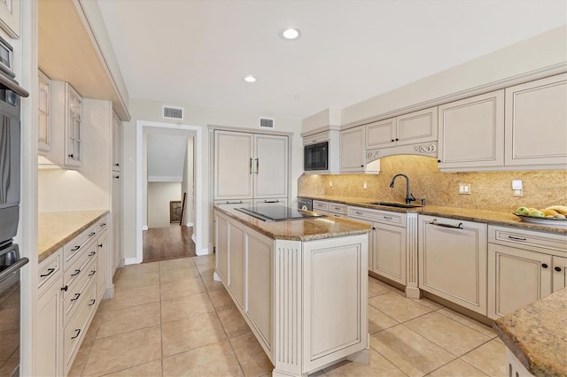 kitchen featuring a sink, visible vents, backsplash, a center island, and black appliances