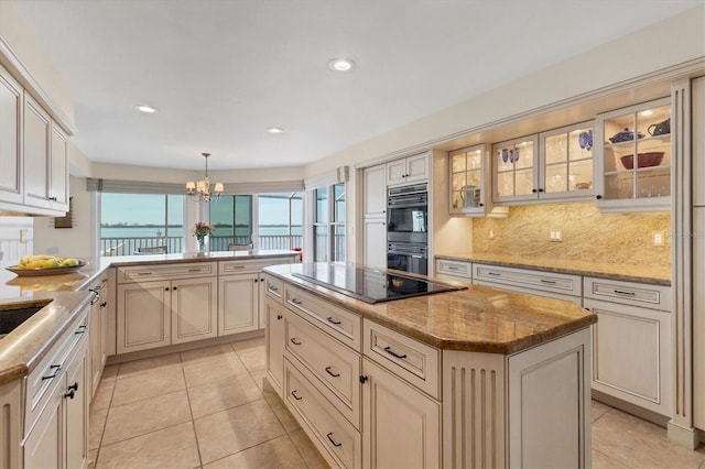 kitchen with decorative backsplash, glass insert cabinets, decorative light fixtures, an inviting chandelier, and black appliances