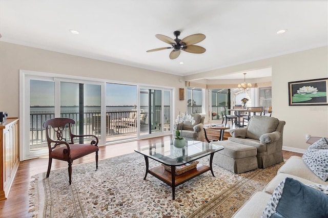 living room featuring recessed lighting, baseboards, wood finished floors, and ceiling fan with notable chandelier