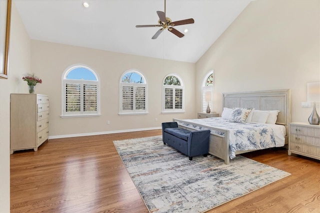 bedroom with high vaulted ceiling, wood finished floors, a ceiling fan, and baseboards