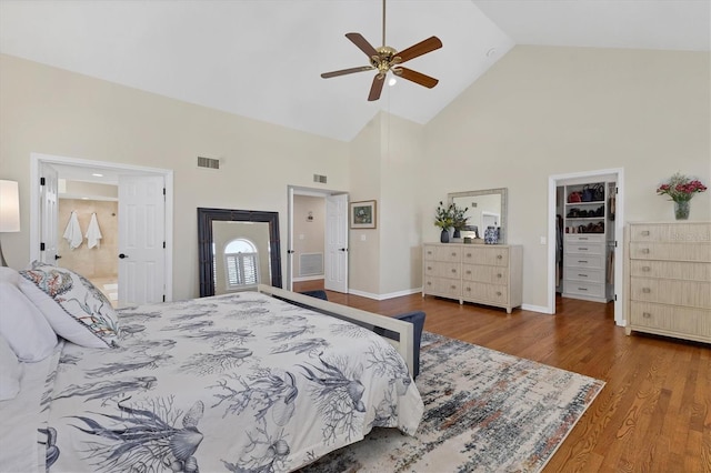 bedroom featuring visible vents, high vaulted ceiling, a walk in closet, and wood finished floors