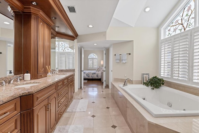 ensuite bathroom featuring a whirlpool tub, tile patterned flooring, visible vents, and a sink