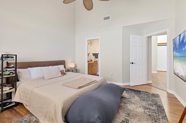 bedroom featuring visible vents, ceiling fan, ensuite bath, wood finished floors, and baseboards