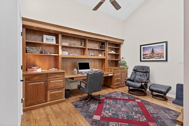 home office with light wood-style flooring, high vaulted ceiling, ceiling fan, and built in desk