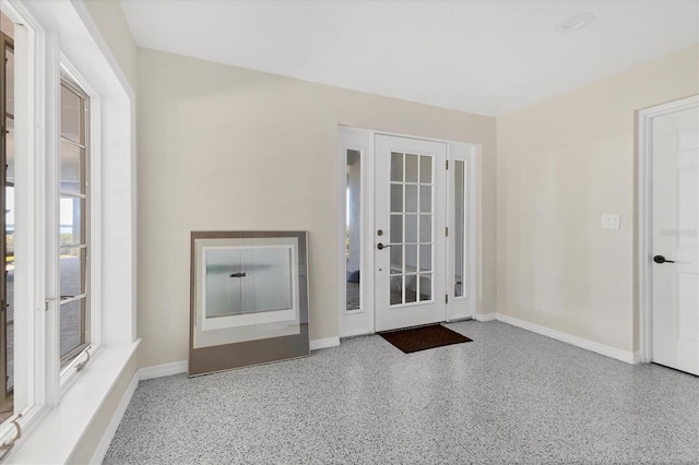 doorway to outside with baseboards and speckled floor