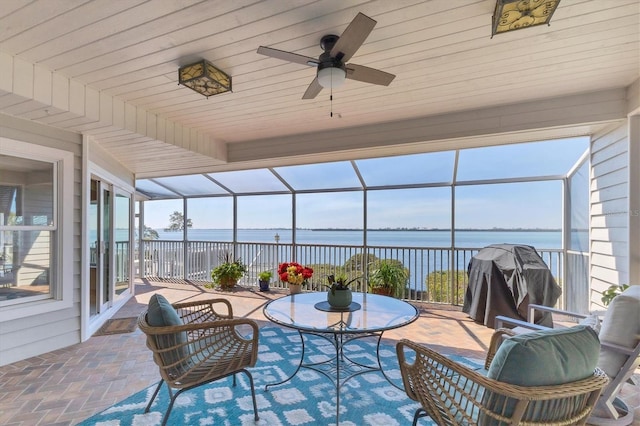 view of patio / terrace with a water view, a lanai, a ceiling fan, and area for grilling