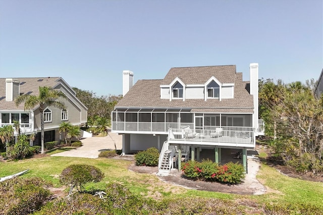 rear view of house featuring a sunroom, a yard, a chimney, and stairs