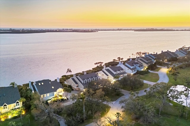 aerial view at dusk featuring a residential view and a water view