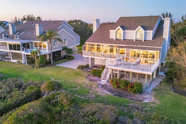 back of property at dusk featuring a yard, a chimney, and stairs