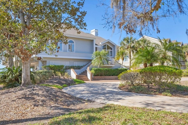 view of front of home with stairs, decorative driveway, and a chimney