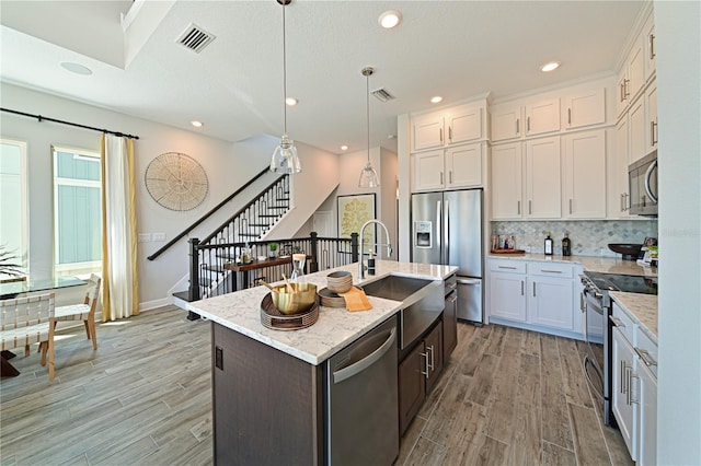 kitchen featuring stainless steel appliances, light wood-style flooring, a sink, and visible vents