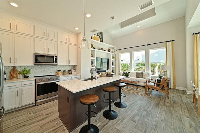 kitchen with visible vents, a sink, stainless steel appliances, light wood-type flooring, and backsplash