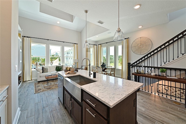 kitchen featuring open floor plan, wood finished floors, visible vents, and dishwasher