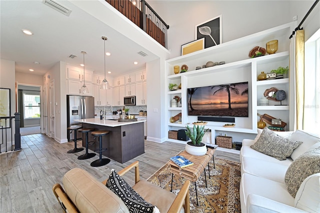 living area with light wood finished floors, visible vents, and baseboards