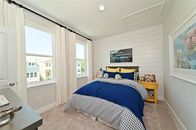 carpeted bedroom featuring wood walls, attic access, and baseboards