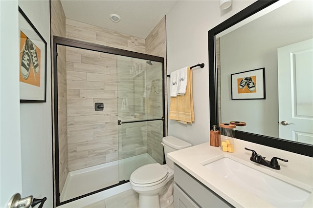 bathroom with vanity, a shower stall, and toilet