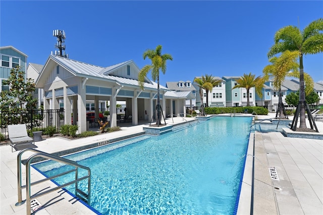 community pool with a residential view, a patio area, and fence