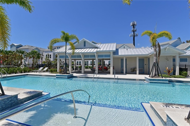 community pool with a patio area, fence, and a residential view