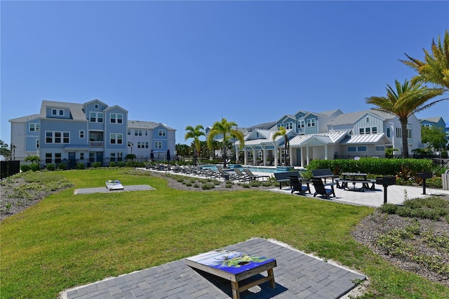 view of property's community with fence, a lawn, a residential view, a swimming pool, and a patio area