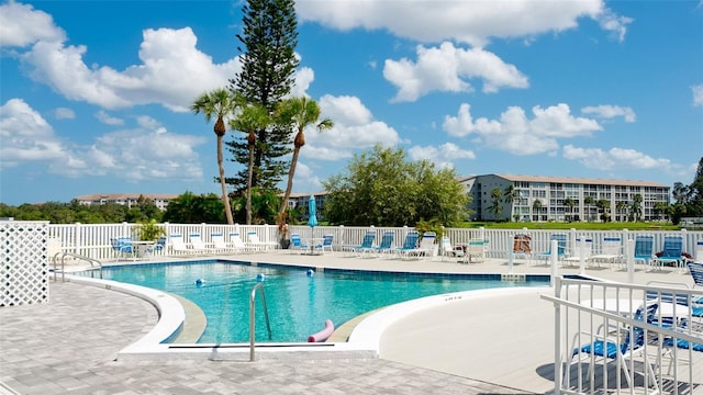 community pool with a patio and fence