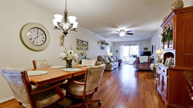 dining area with ceiling fan with notable chandelier, dark wood-style floors, and a textured ceiling