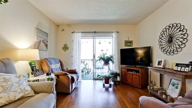 living room featuring dark wood-style flooring and a textured ceiling