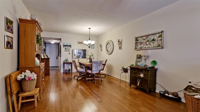 dining space featuring a notable chandelier, a textured ceiling, baseboards, and hardwood / wood-style floors