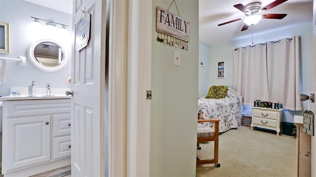 bedroom featuring a textured ceiling, a ceiling fan, a sink, and light carpet