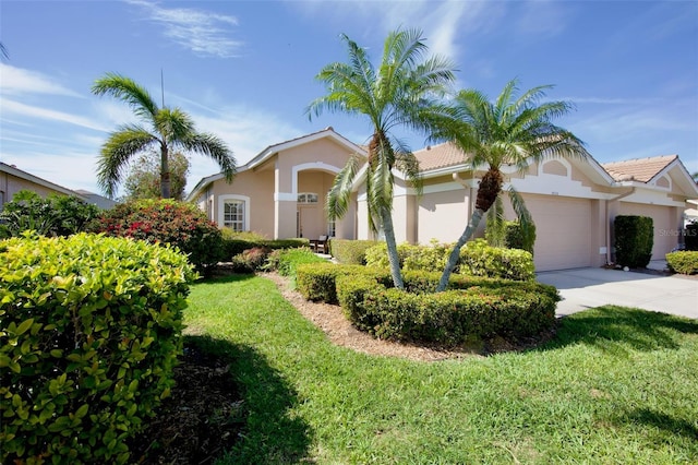 view of front of property featuring a front yard, concrete driveway, an attached garage, and stucco siding