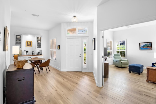 entryway with light wood finished floors, visible vents, and baseboards