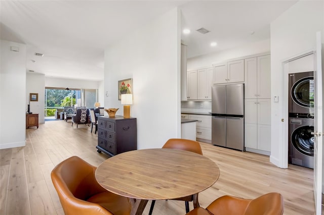 dining area featuring light wood-type flooring, visible vents, and stacked washer / drying machine