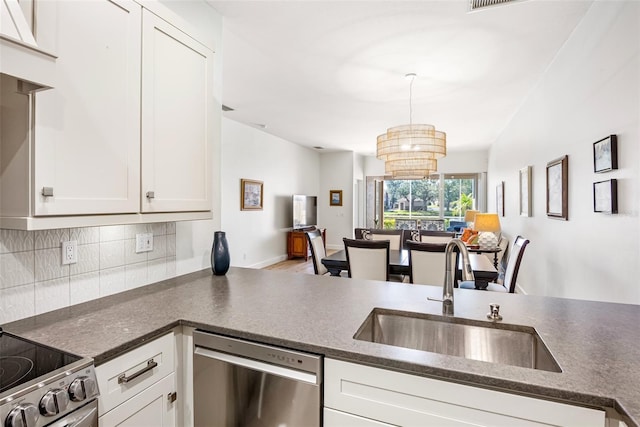 kitchen featuring pendant lighting, tasteful backsplash, appliances with stainless steel finishes, white cabinetry, and a sink