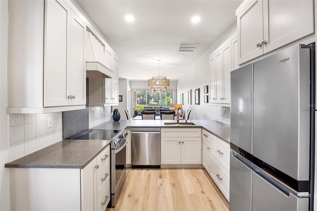 kitchen with visible vents, dark countertops, appliances with stainless steel finishes, light wood-type flooring, and a sink