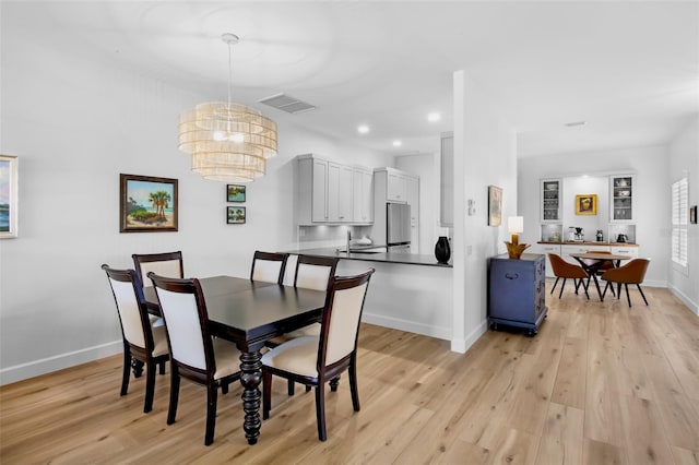 dining area featuring baseboards, a chandelier, visible vents, and light wood-style floors