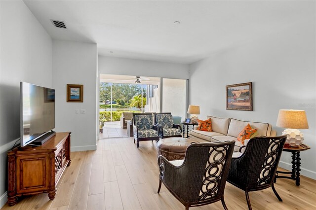 living room with light wood-type flooring, visible vents, and baseboards