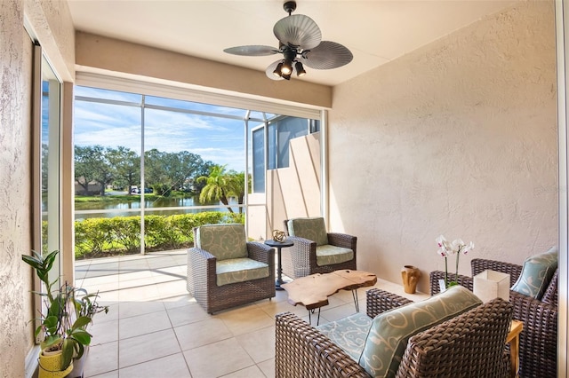 interior space with light tile patterned floors, a textured wall, a sunroom, ceiling fan, and a water view