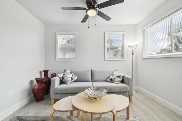 living room with light wood-type flooring, baseboards, and a ceiling fan