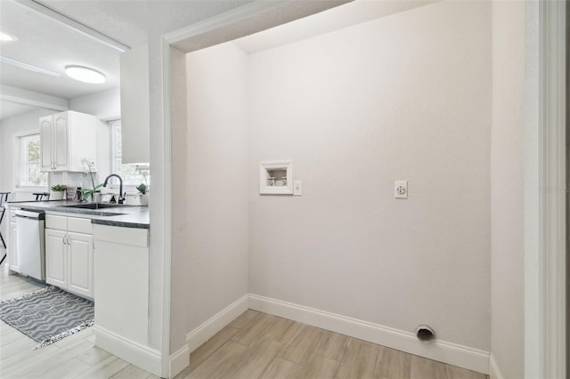 laundry room with light wood-style floors, laundry area, a sink, and baseboards