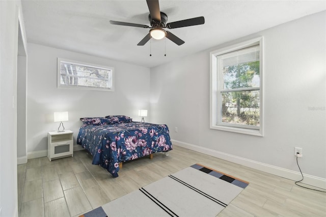 bedroom featuring ceiling fan, multiple windows, wood finished floors, and baseboards