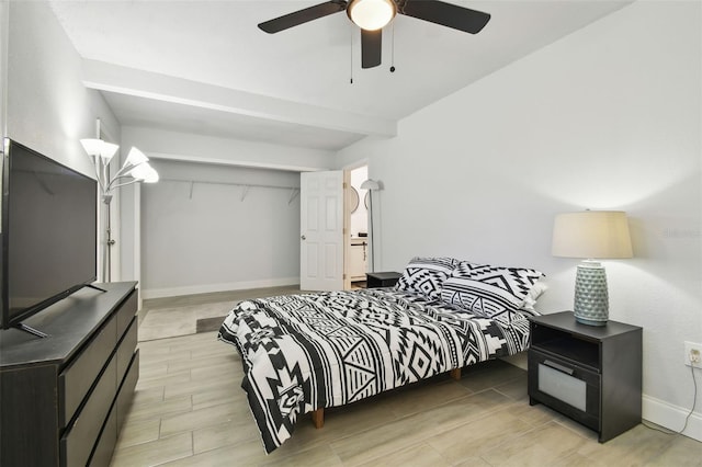 bedroom featuring a closet, a ceiling fan, wood tiled floor, beamed ceiling, and baseboards