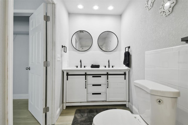 bathroom featuring double vanity, wood finished floors, a sink, and toilet