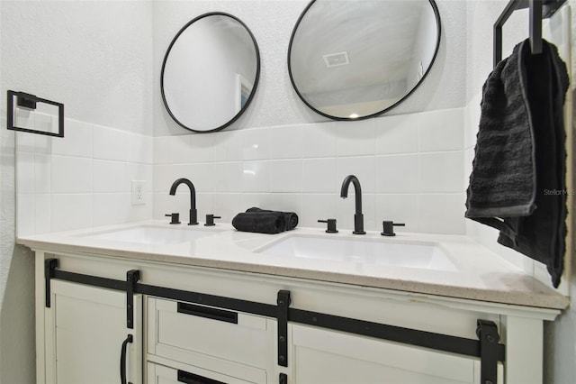 bathroom with a textured wall, a sink, tile walls, and double vanity