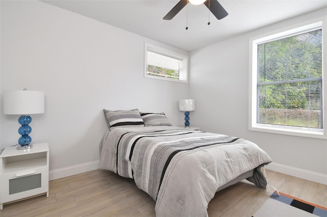 bedroom featuring light wood-type flooring, a ceiling fan, and baseboards