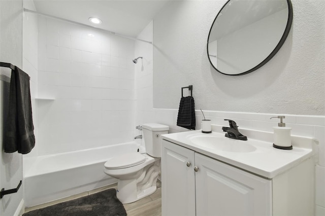 bathroom featuring a textured wall, shower / bathing tub combination, toilet, vanity, and wood finished floors