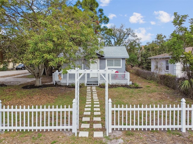 view of front of house with a fenced front yard, a shingled roof, and a wooden deck