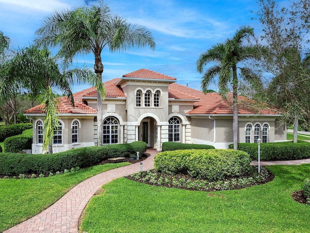 mediterranean / spanish home featuring a tiled roof, a front yard, and stucco siding