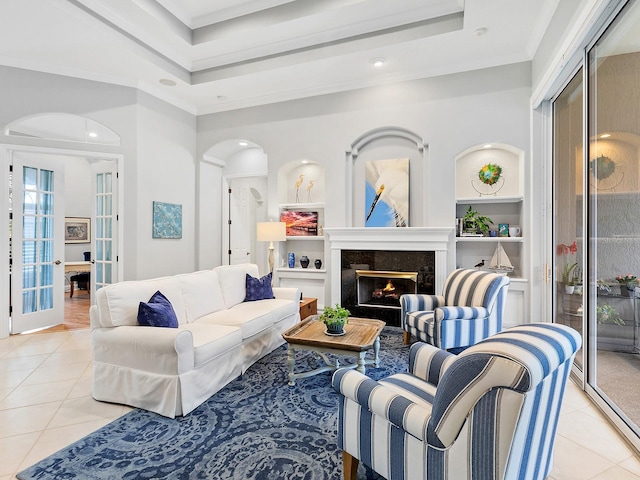 living room with light tile patterned floors, arched walkways, a premium fireplace, ornamental molding, and a tray ceiling