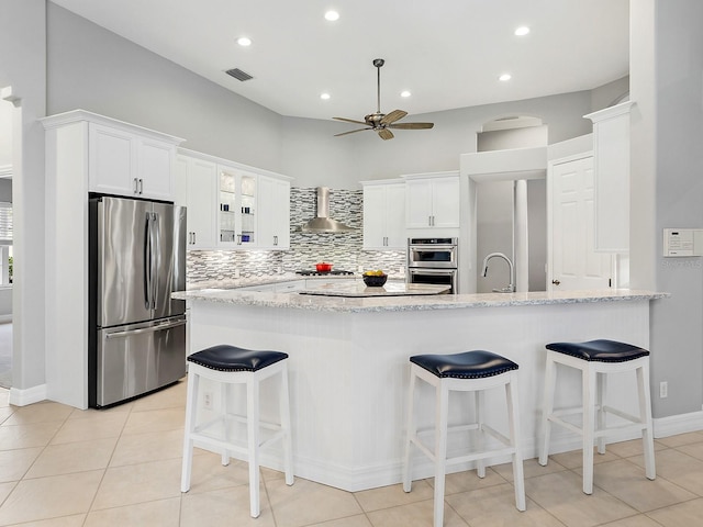 kitchen featuring stainless steel appliances, visible vents, backsplash, glass insert cabinets, and wall chimney range hood